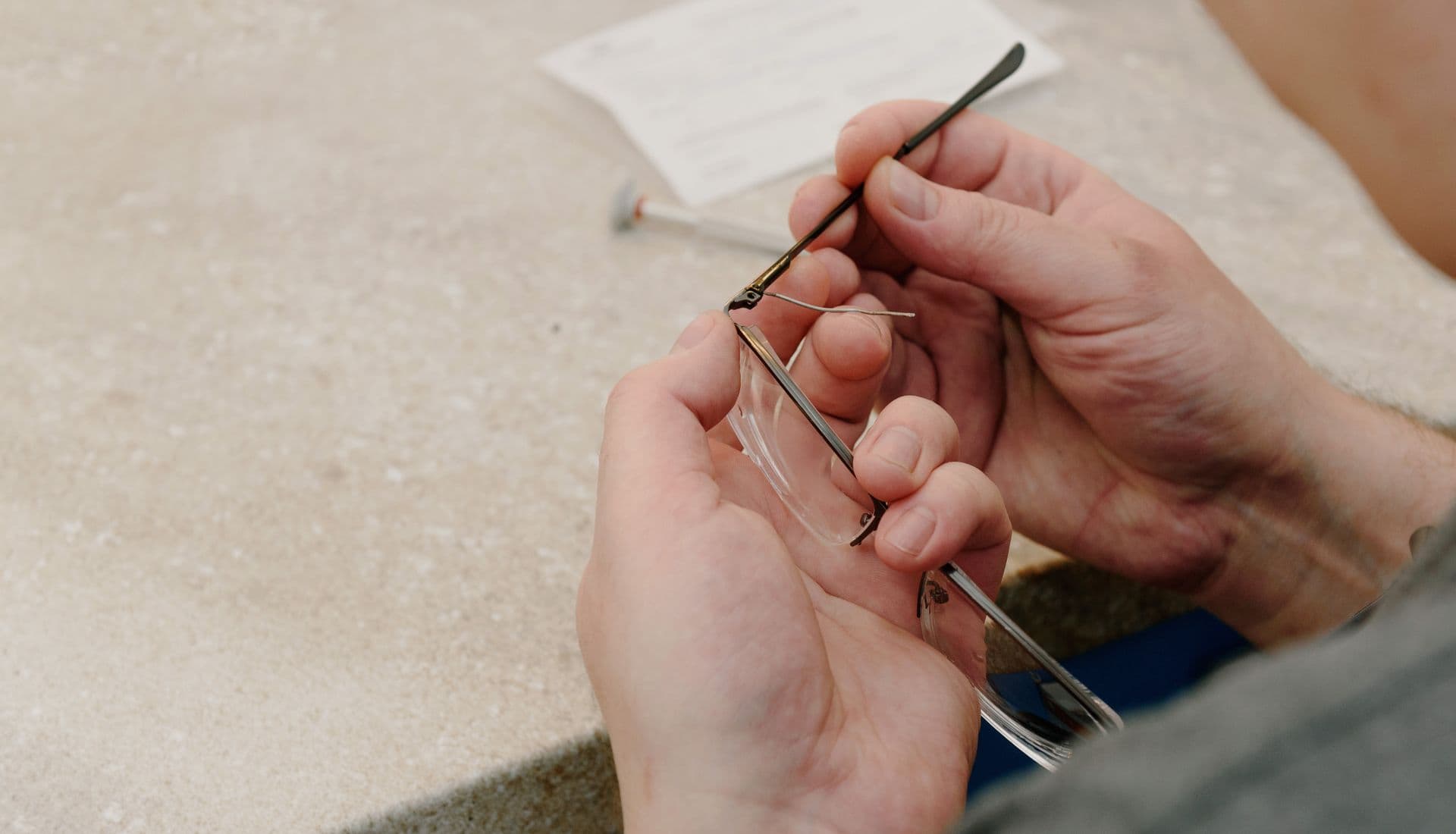 Des mains qui resserrent la branche d'une paire de lunettes